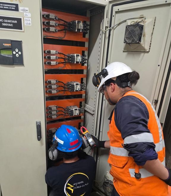 Two technicians measuring inside a switchboard