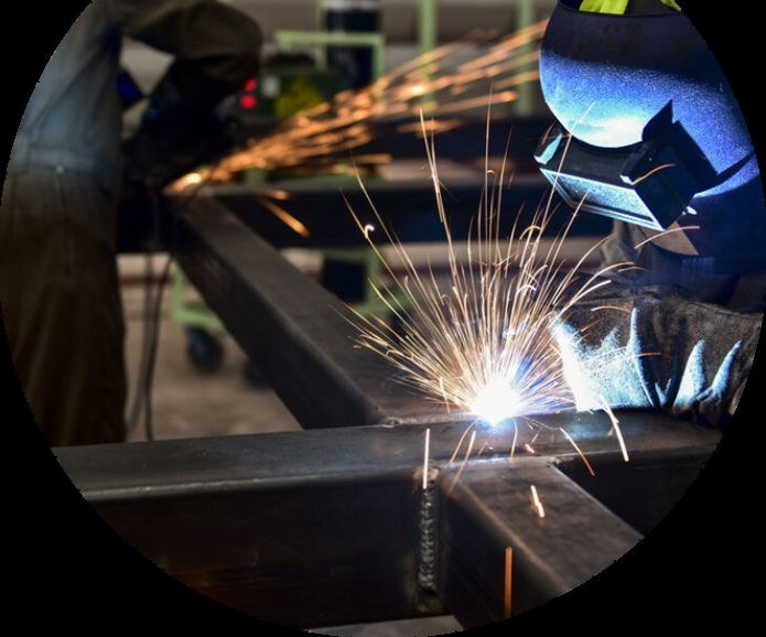 Welder joining steel beams with sparks flying